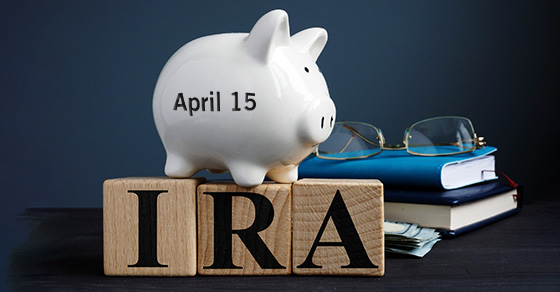 piggy bank with April 15 written on it standing on top of wooden blogs reading IRA