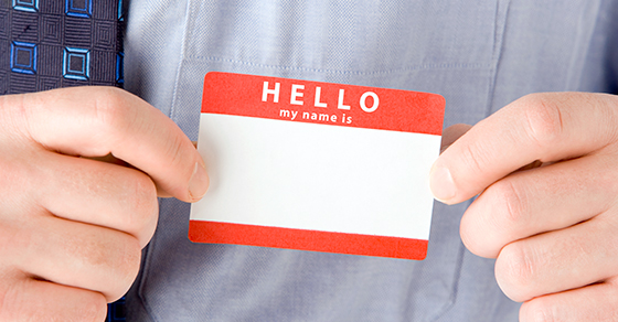 close up of hands holding sticker name badge that says Hello my name is with a blank space to fill in your name.