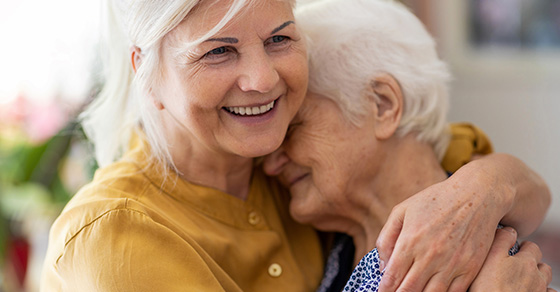Older women hugging elderly mother while smiling