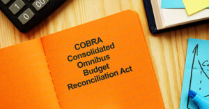 orange notebook with COBRA Consolidated Omnibus Budget Reconciliation Act 