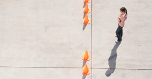 person standing at opening in a line of traffic cones blocking a sidewalk