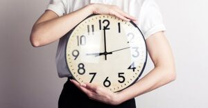 close up of person holding large clock with hands showing time as 9:00