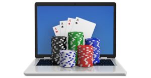 laptop open with 4 ace playing cards in front of the screen and 5 stacks of poker chips in the following colors in front of the cards - black, green, blue, while, red