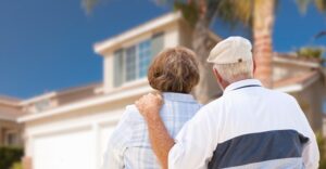 elderly couple shown from behind looking at house
