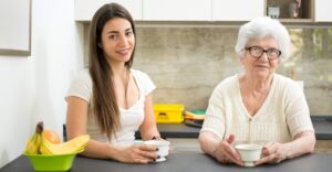 younger woman sitting with elderly woman over coffee