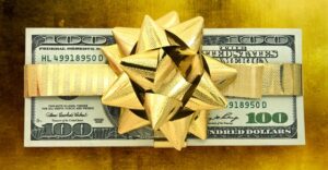 stack of $100 bills with gold ribbon and bow on it