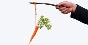 Businessman hand holding Carrot on a stick isolated on white background. Carrot and stick reward and punishment concept.