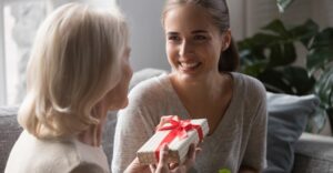 older woman giving younger woman a small gift wrapped with a bow