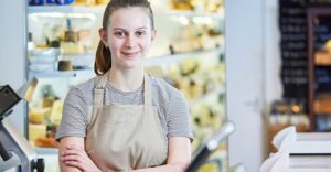 teen worker standing smiling while wearing cashier apron