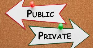Private vs Public words on paper arrow pinned on cork board. Business Concept