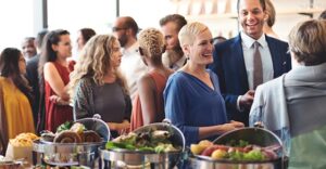 group of people at a buffet style fundraiser smiling and chatting