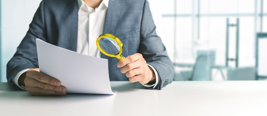 businessman or tax inspector analyzing document with magnifying glass in office, possible re-compete. business financial audit concept. copy space