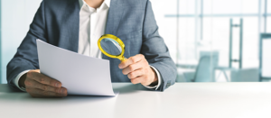 businessman or contractor analyzing document with magnifying glass in office. business financial audit concept. 