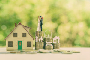 Sustainable financial goal for family life or married life concept : community property:  Miniature wedding couple, parent & child, a house or home, a car on rows of rising coins, depicts savings or growth for new family 