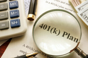 Document with title 401k plan on a table. 401(k) Plan is in magnifying glass