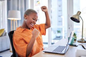 Happy woman cheering with fist bump for meeting financial goals