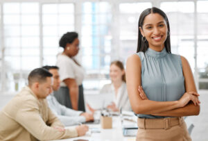 Smiling, happy and motivated young business woman with arms crossed showing great leadership to her team in an office. Portrait of confident and proud entrepreneur satisfied with growth in a startup.
