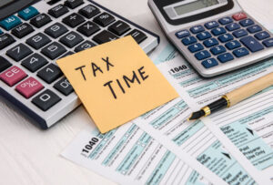 Tax time written on a sticky note on 1040 individual tax form

