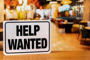 Help wanted sign inside restaurant. Food service industry jobs, labor shortage and unemployment concept highlighting worker shortage
