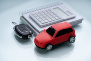 toy car next to a small notepad with a calculator on top of it. Car keys are next to notepad. Indicating keeping records for mileage reimbursement