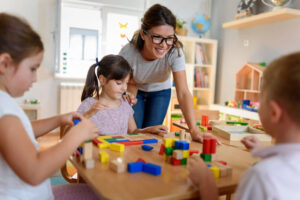 daycare teacher with children playing with colorful wooden didactic toys at daycare center