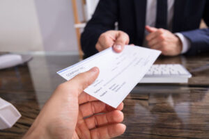 close up of employer handing paycheck to employee