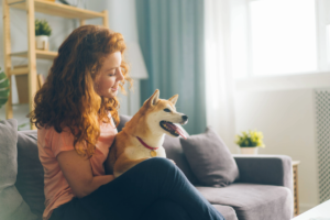 women sitting on couch in apartment smiling with dog sitting next to her