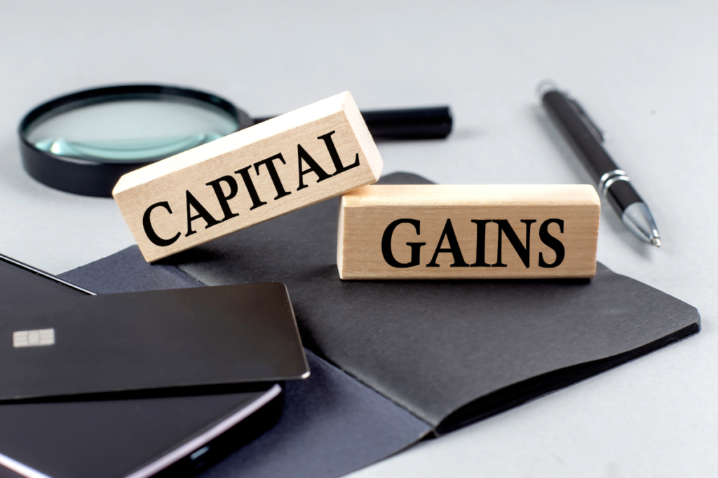 CAPITAL GAINS text on wooden block on black notebook , business concept of tax on capital gains