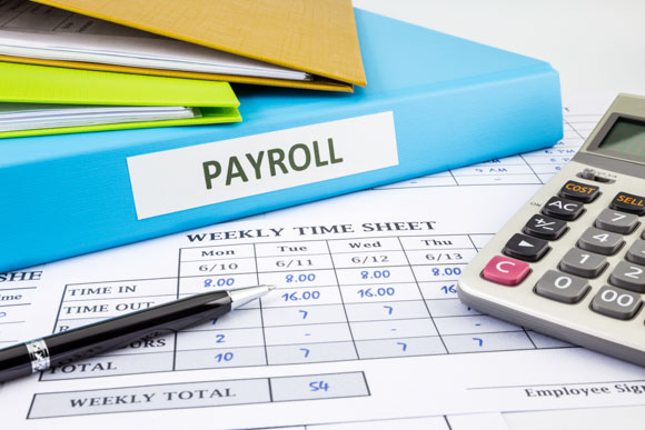 PAYROLL word on blue binder place on weekly time sheet and payroll summary report with overtime tracking