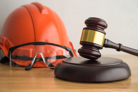 a judge’s gavel next to a hard hat and safety glasses. This imagery connects to the legal aspects of the FTC’s ruling on noncompete agreements and could represent both workers’ rights (represented by the gavel) and workplace safety (represented by the hard hat and safety glasses).