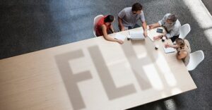 four people sitting at table, two on each side. Letters FLP showing on table as a shadow