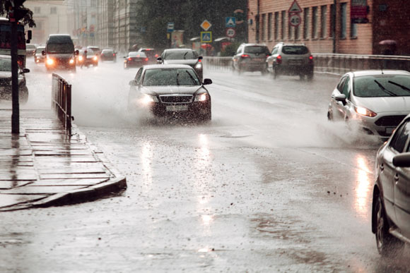 Cars drive through a flooded street during severe rainy weather
